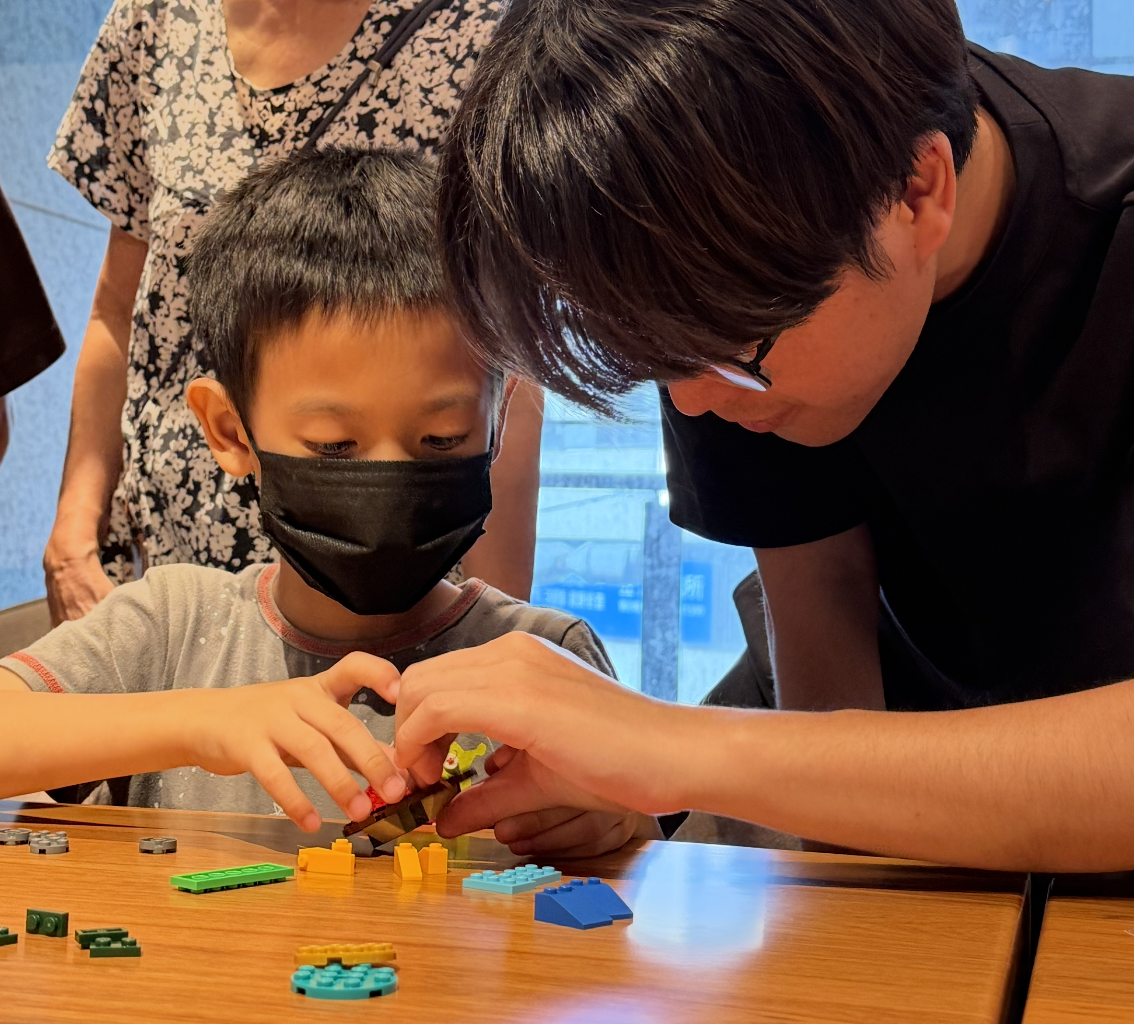 大哥哥陪伴孩子在桌邊一起拼樂高積木